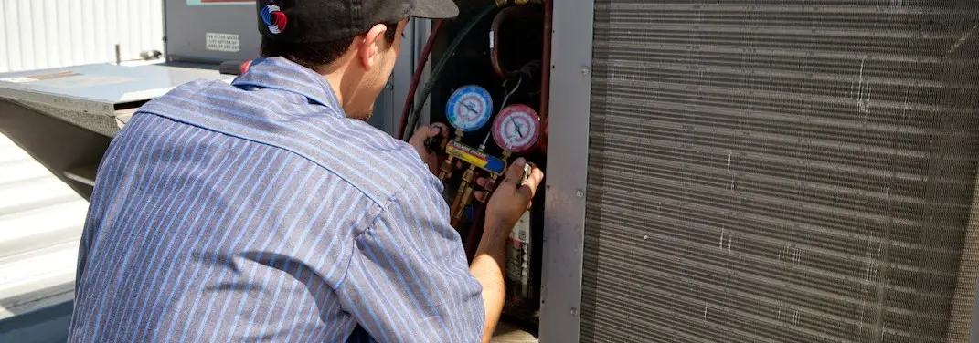 HVAC technician servicing a condenser unit in West Lafayette